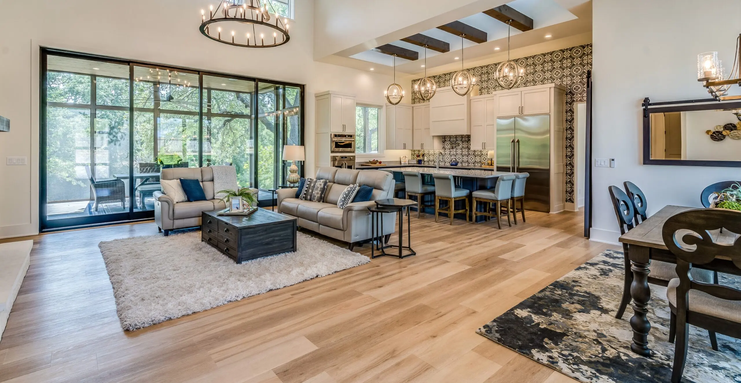 Two story great room with nice chandelier and large glass sliding doors opening up completely to sunroom patio