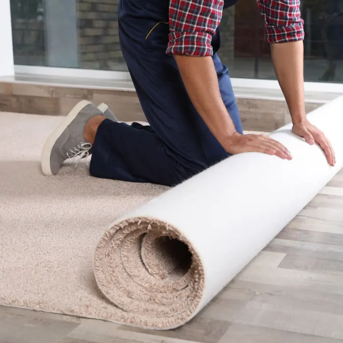 Man rolling out new carpet flooring indoors, closeup