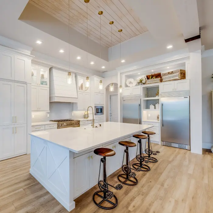 A beautifully designed kitchen featuring sleek white cabinetry, modern appliances, and a spacious island with stylish bar stools, creating the perfect space for culinary creations and family gatherings.