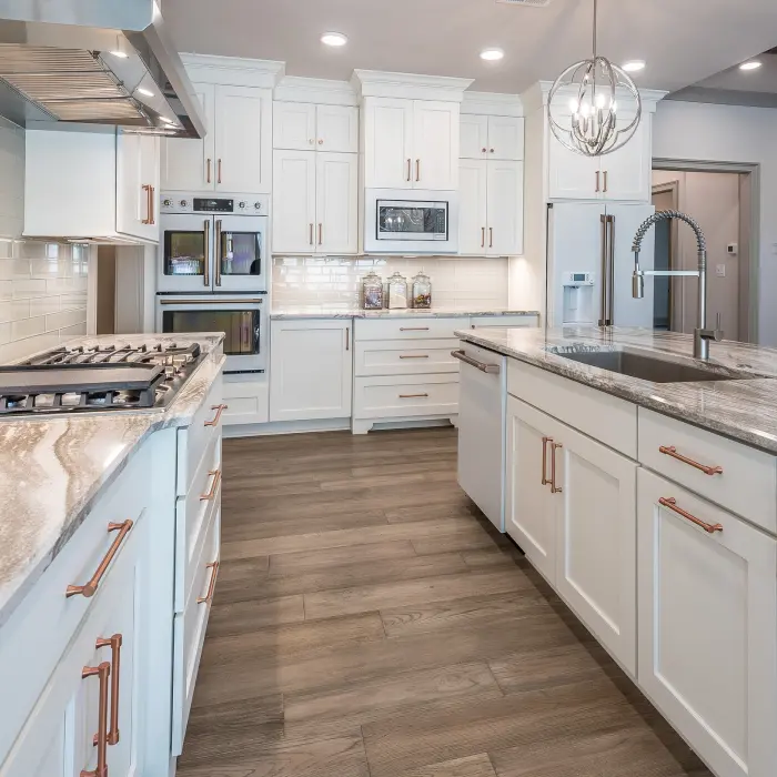 A spacious modern kitchen featuring sleek white cabinetry, elegant marble countertops, and stylish copper accents.