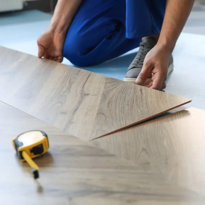 Worker installing laminated wooden floor indoors, closeup
