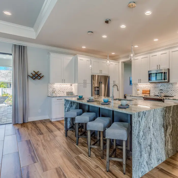 A modern kitchen combines elegance and functionality, featuring a stunning marble island surrounded by comfortable seating.