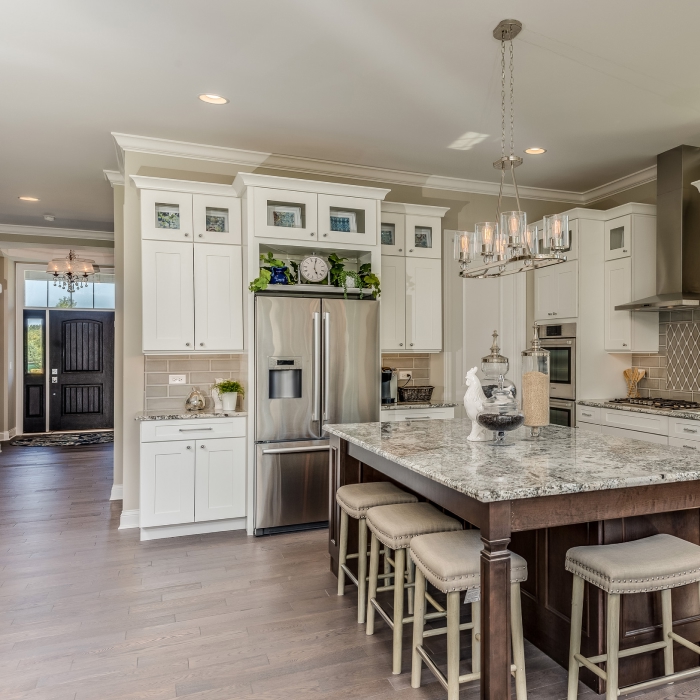 A bright and airy kitchen showcases modern elegance, featuring a spacious island with a stunning granite countertop and stylish bar stools.